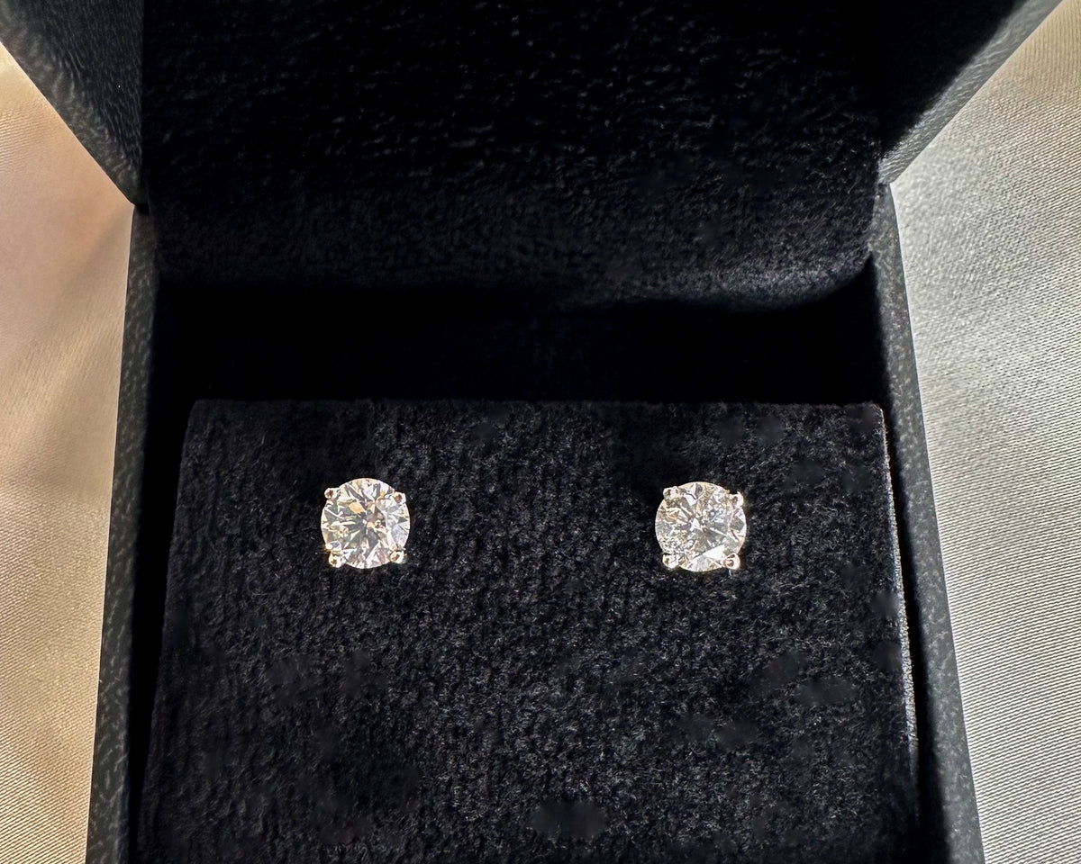 Pair of round brilliant diamond stud earrings in a black jewelry gift box