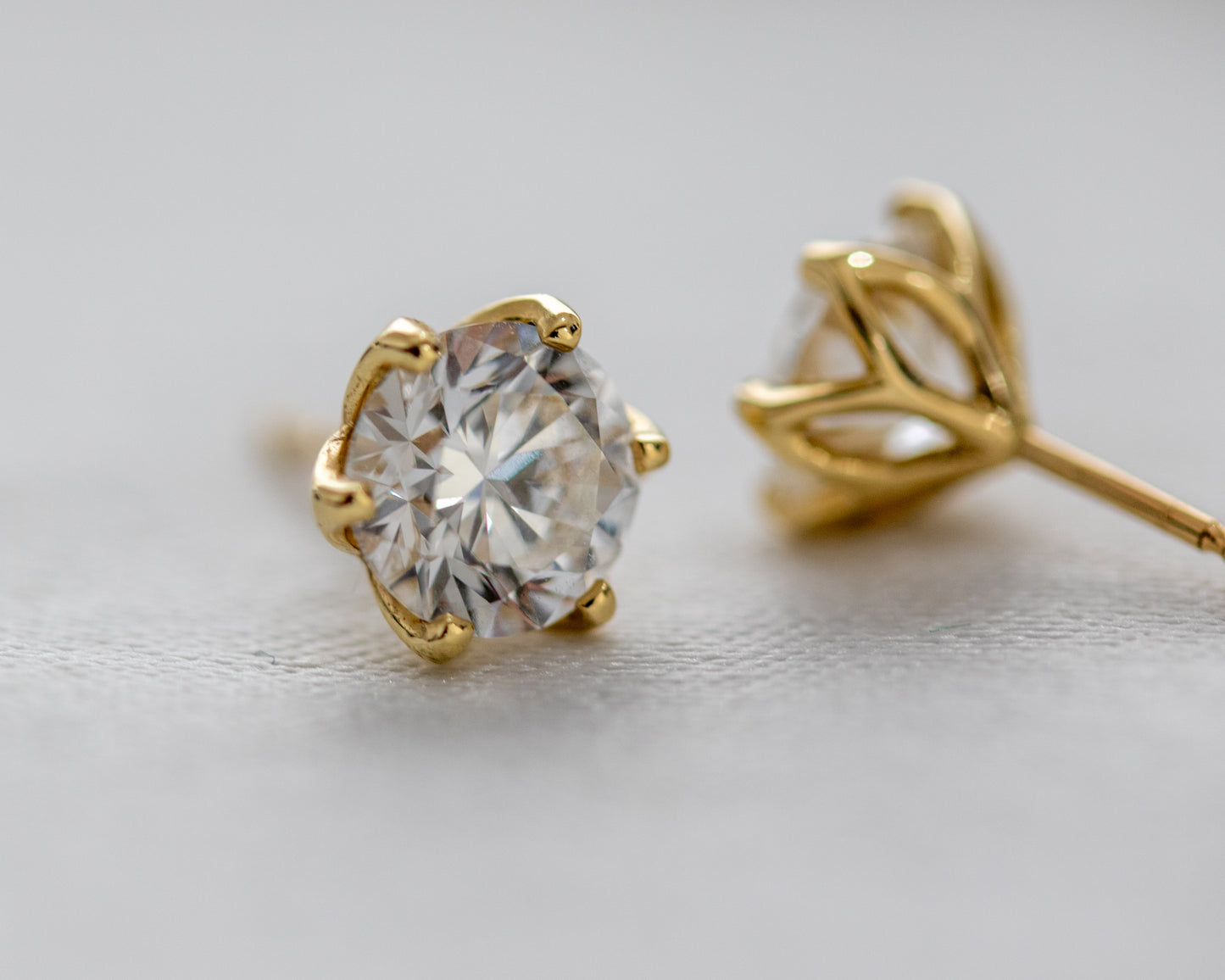 Pair of round diamond stud earrings in solid 14K gold, angled view
