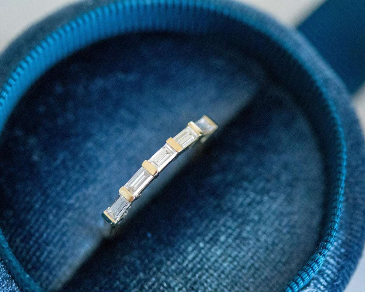 Five-stone east-west baguette diamond ring in 14K yellow gold in a blue velvet ring box