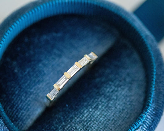 Five-stone east-west baguette diamond ring in 14K yellow gold in a blue velvet ring box