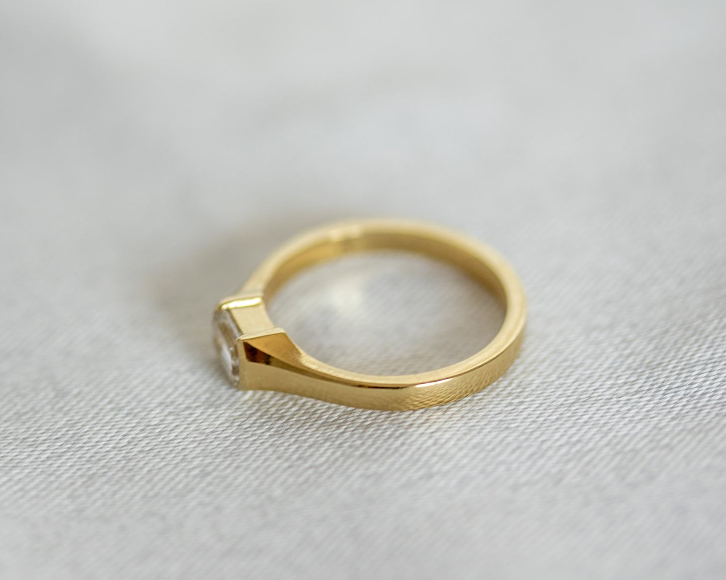 Gold ring with a diamond on a light gray background