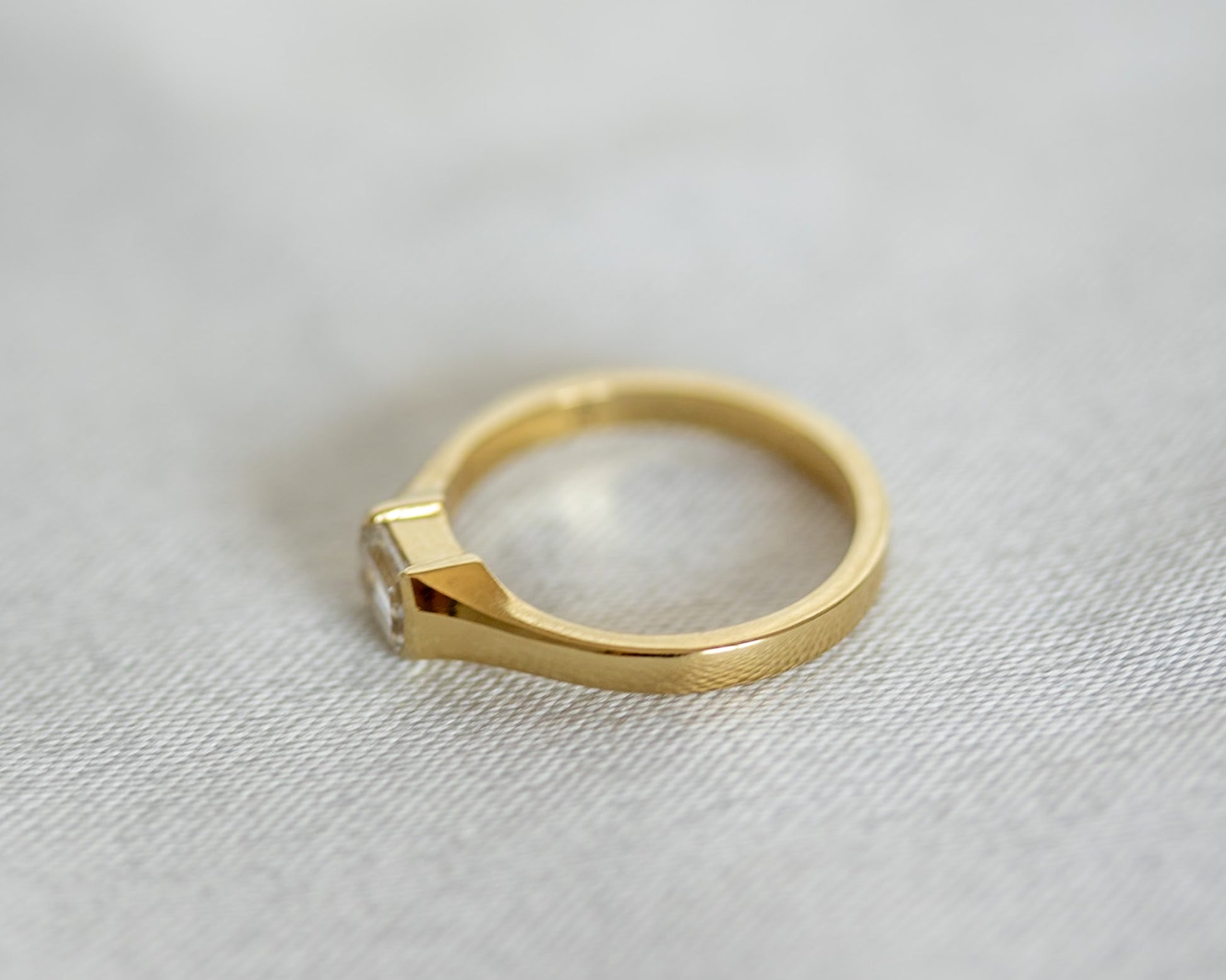 Gold ring with a diamond on a light gray background
