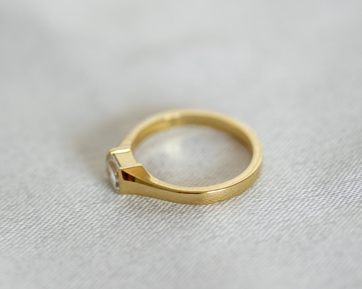 Emerald cut diamond ring in 14K yellow gold, half bezel setting