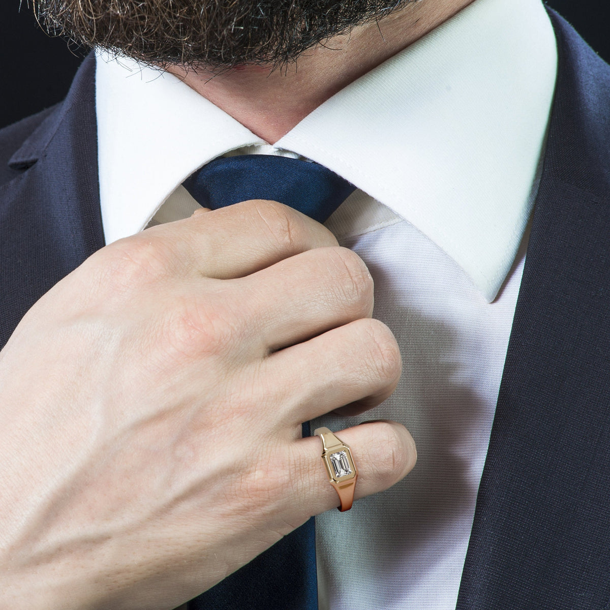 Gold signet ring with an east-west emerald cut diamond, worn with a suit and tie