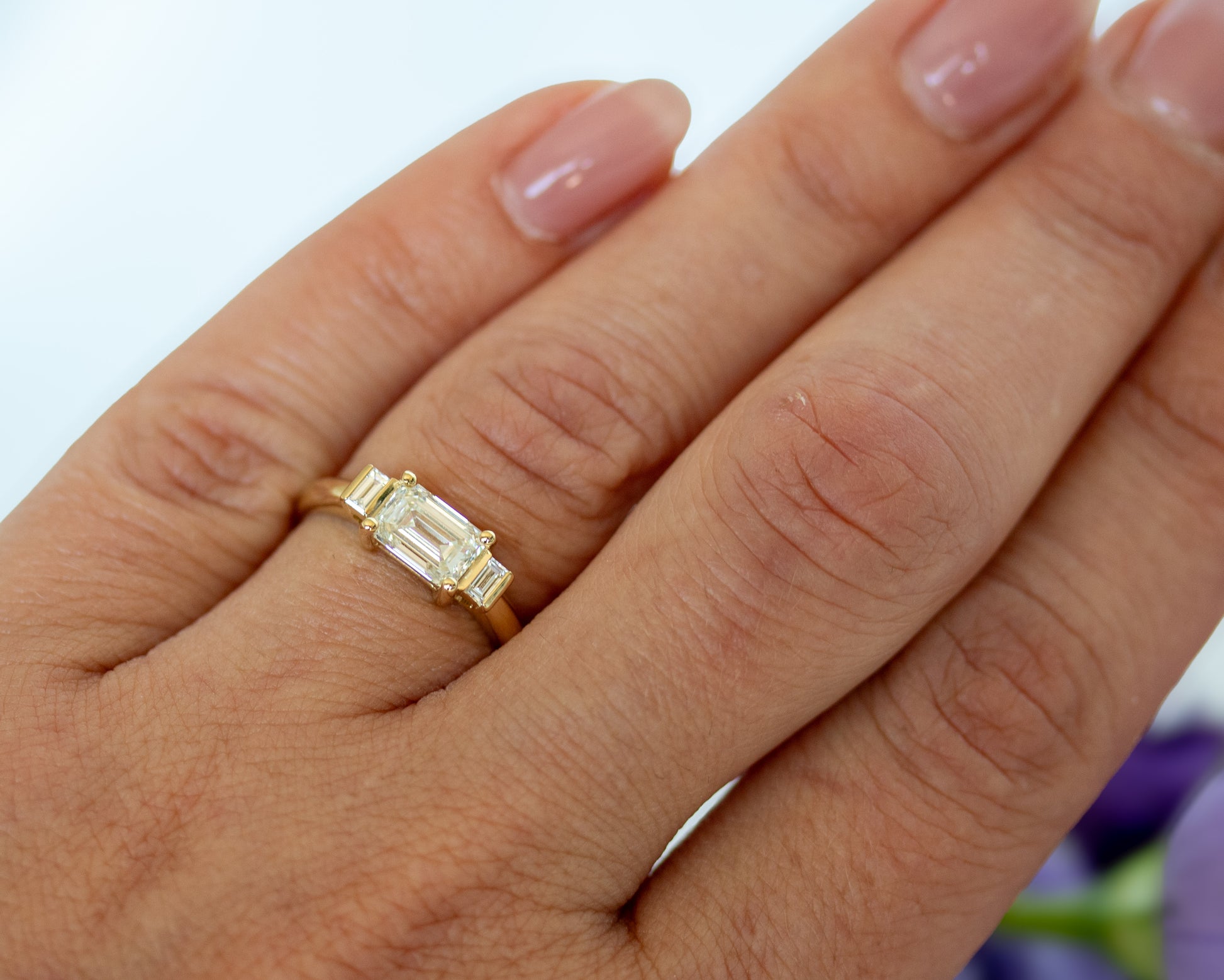 Emerald cut diamond trilogy ring worn on hand, natural light
