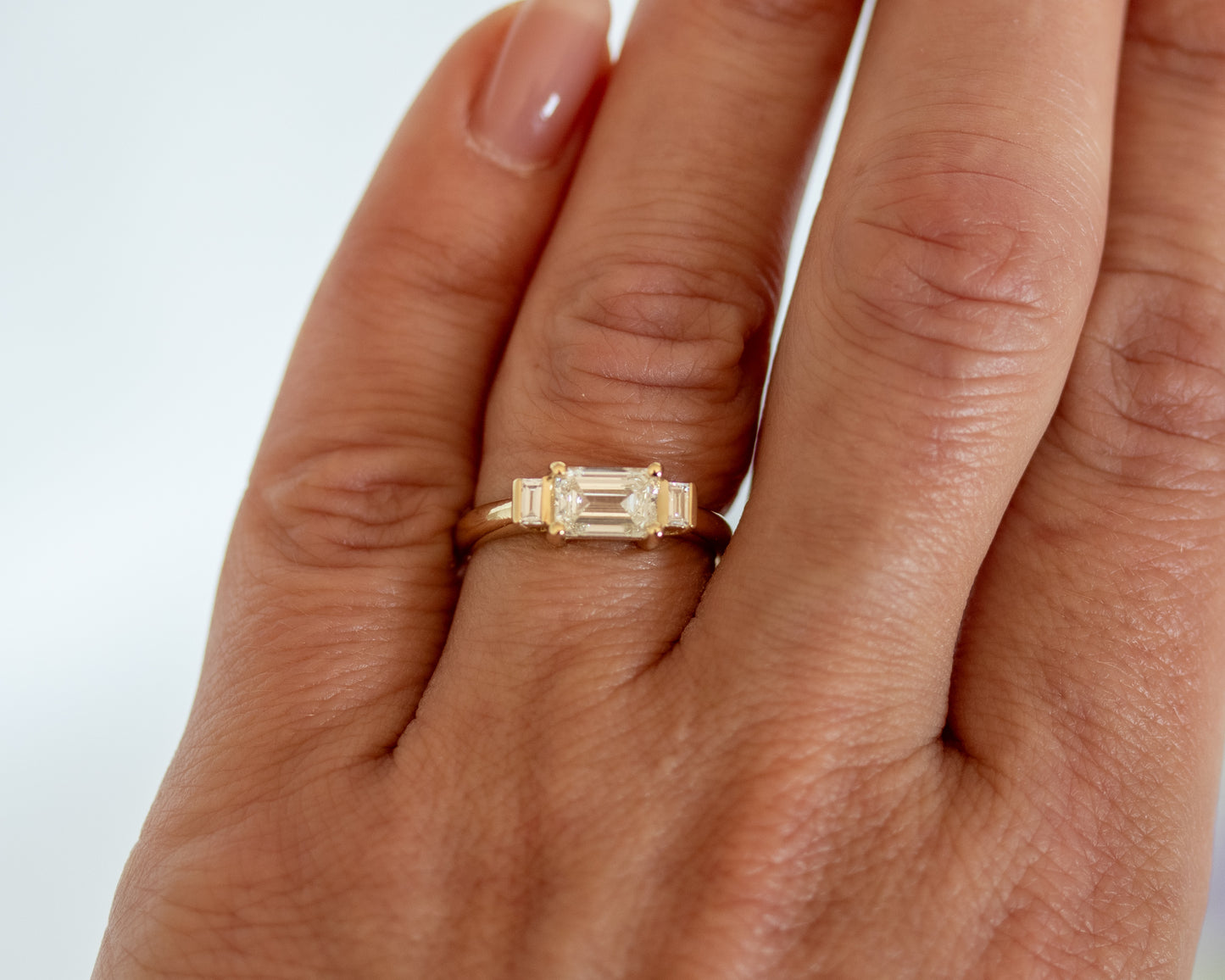 Emerald cut diamond trilogy ring worn on hand, side angle