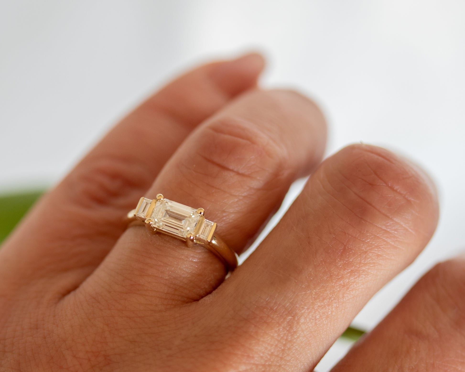 Emerald cut diamond trilogy ring worn on hand, top view