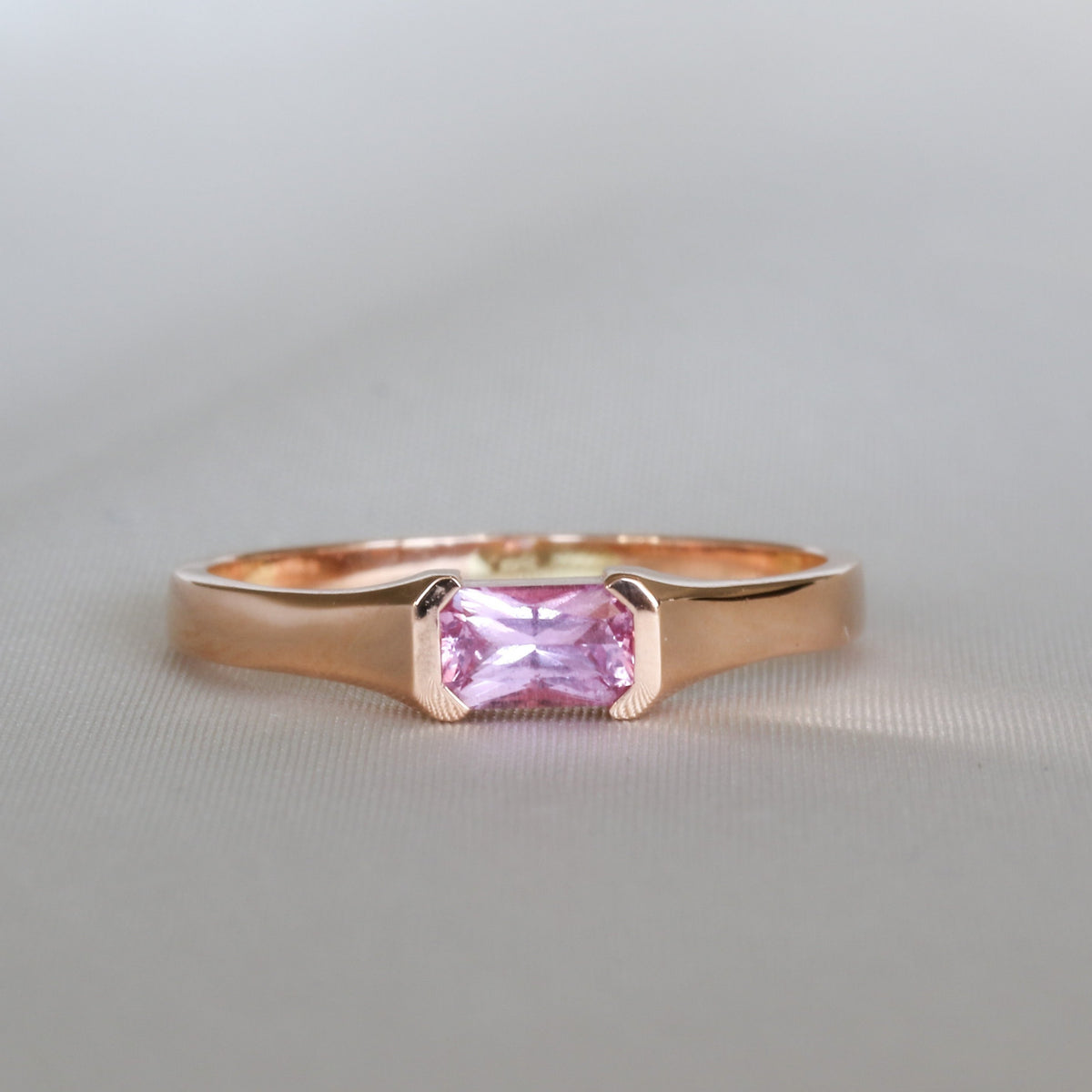 Emerald cut pink sapphire in a half bezel, 14K rose gold ring