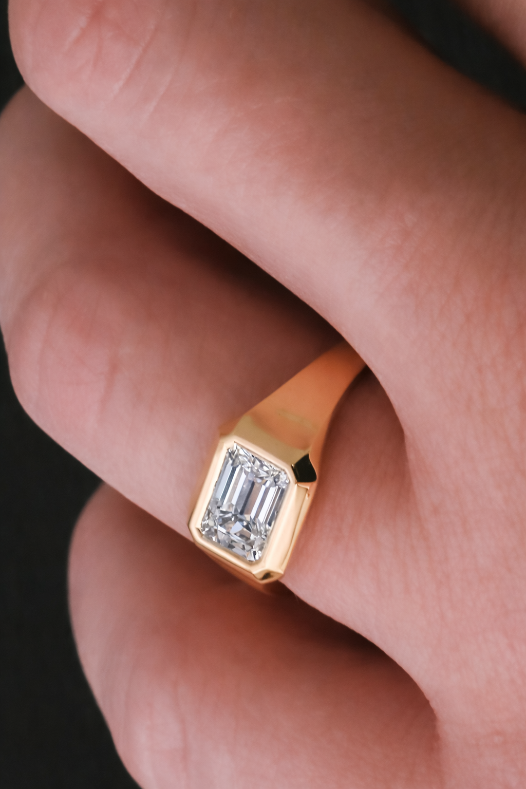 Gold emerald-cut diamond signet ring worn on the hand