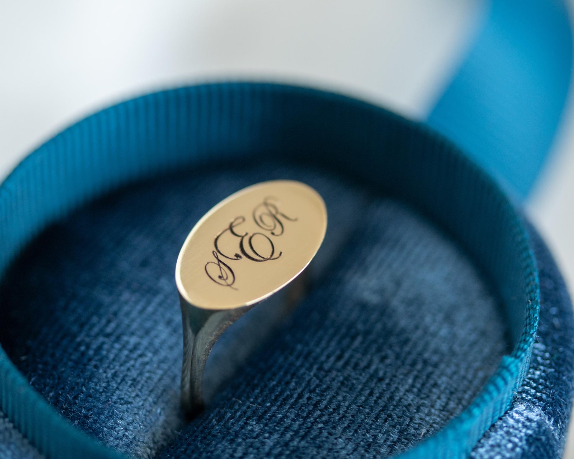 Gold ring with 'SER' engraving on a blue cushion