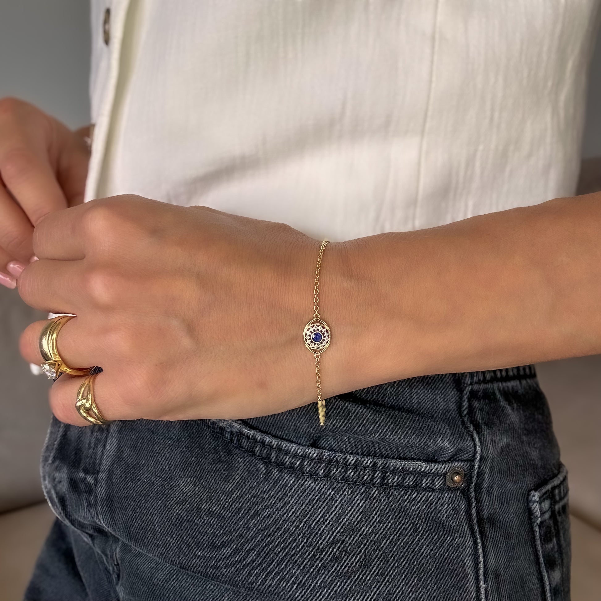 A person wearing a 14K gold sapphire and diamond bracelet on their wrist.