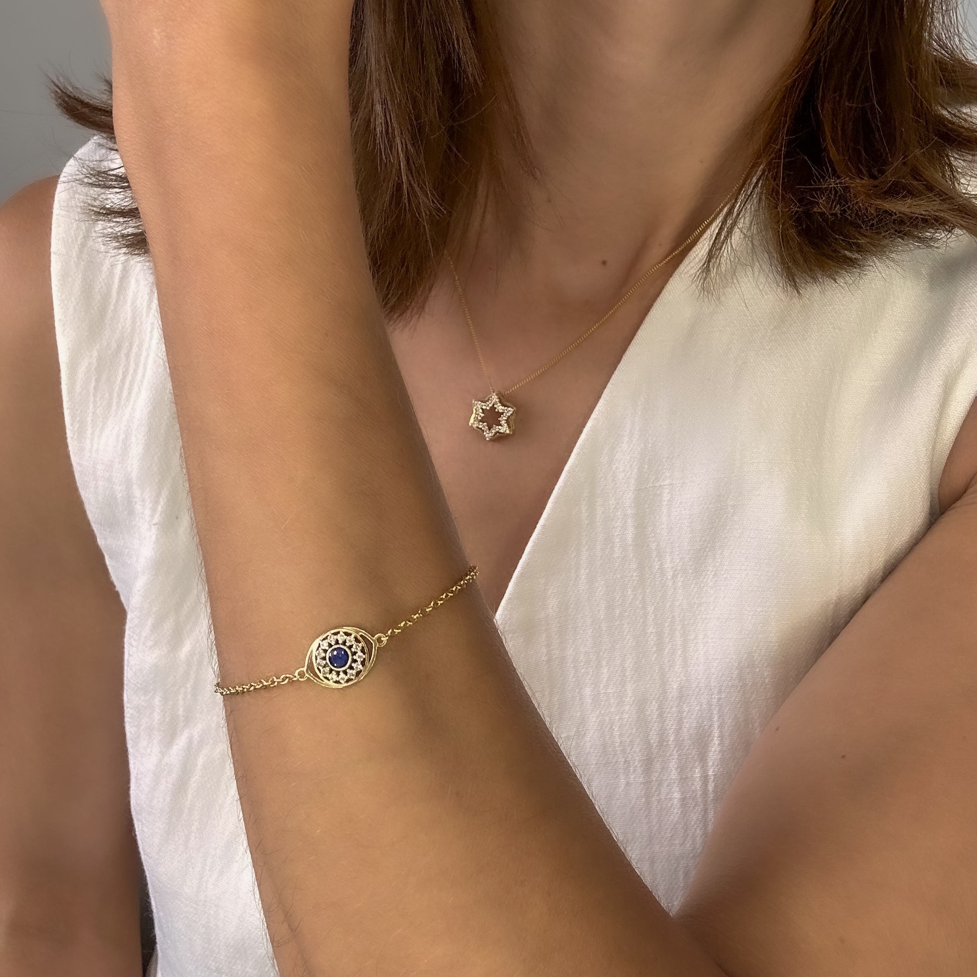 14k gold bracelet with evil eye charm with blue sapphire and natural diamonds on womens wrist 