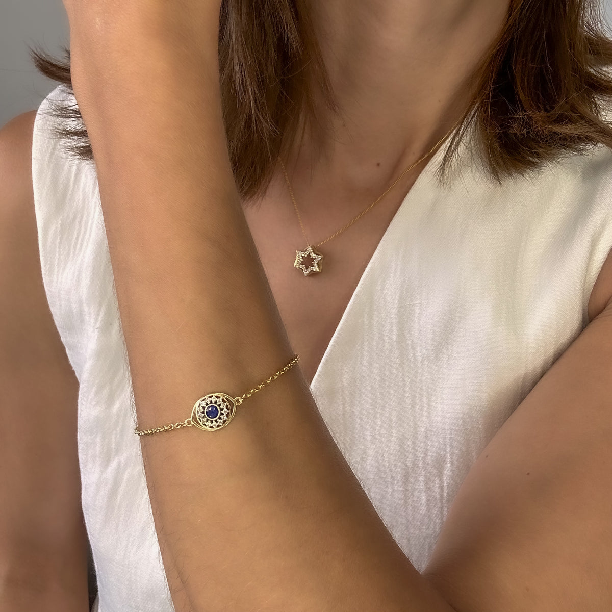 14K yellow gold evil eye diamond bracelet worn on the wrist with a white top