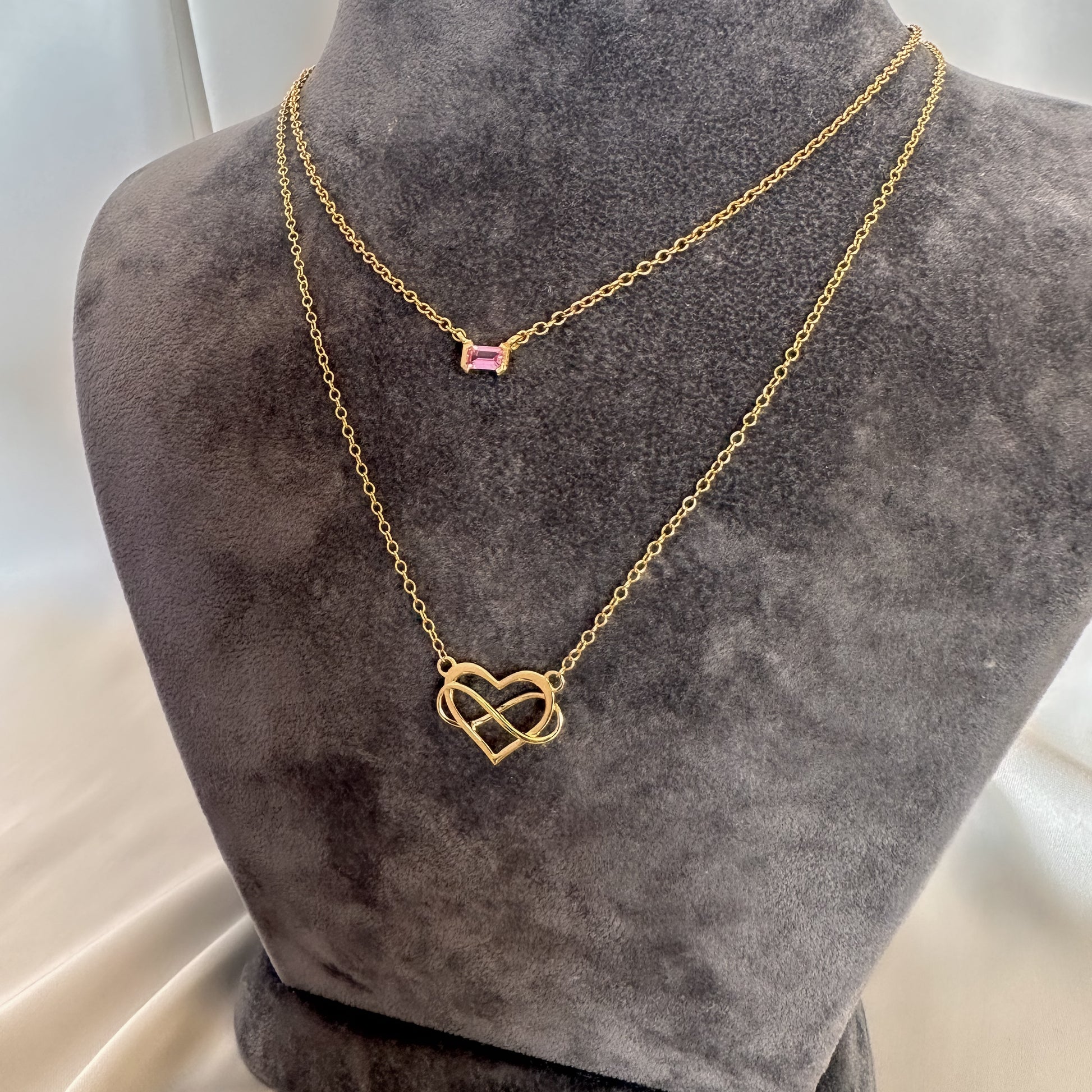 yellow gold heart and infinity symbol pendant and chain and yellow gold pink sapphire choker on gray velvet tourso