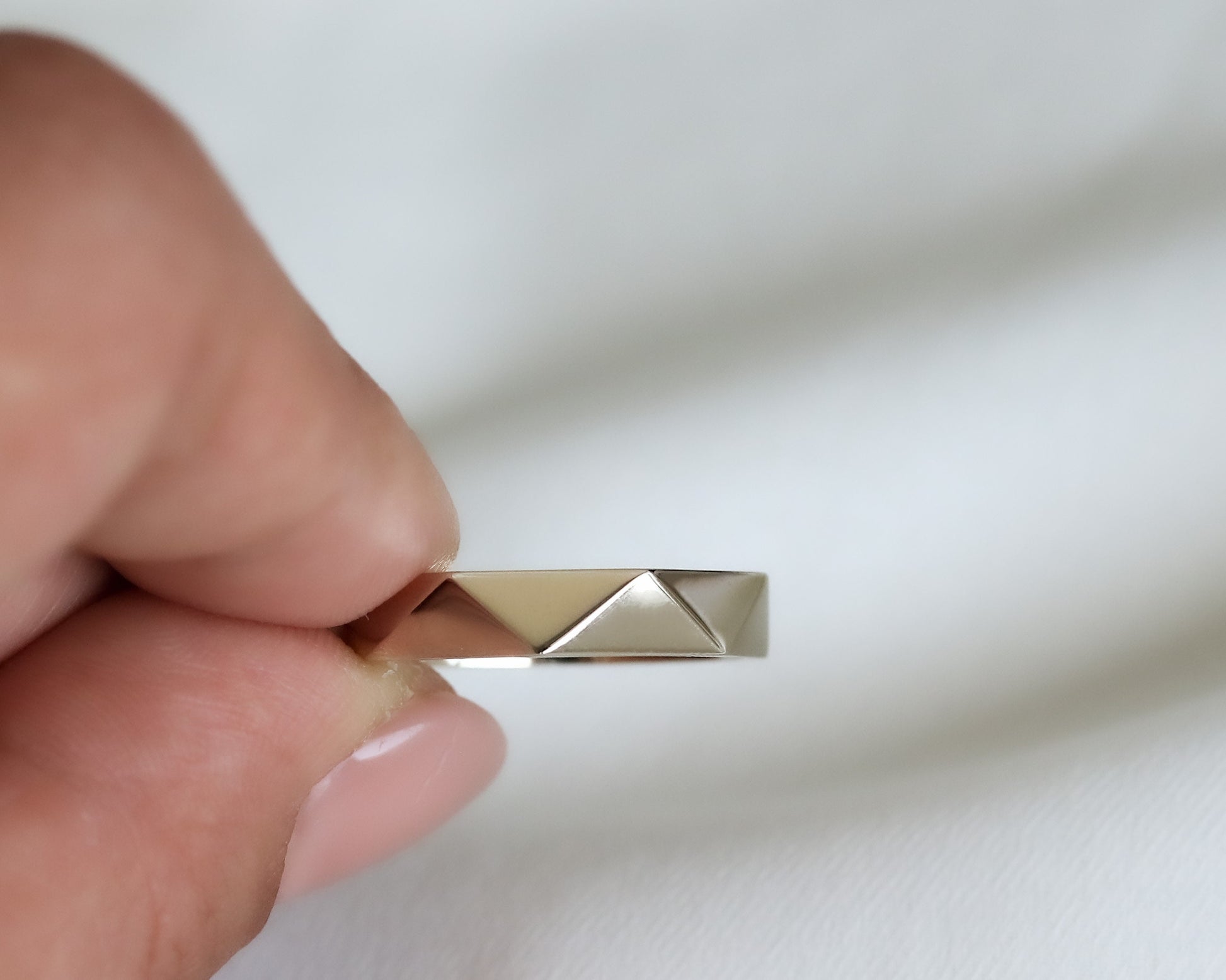 fingers holding faceted gold ring edge view