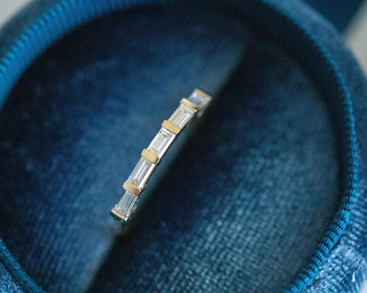 Five baguette diamonds bar-set east-west in a 14K yellow gold ring, close-up