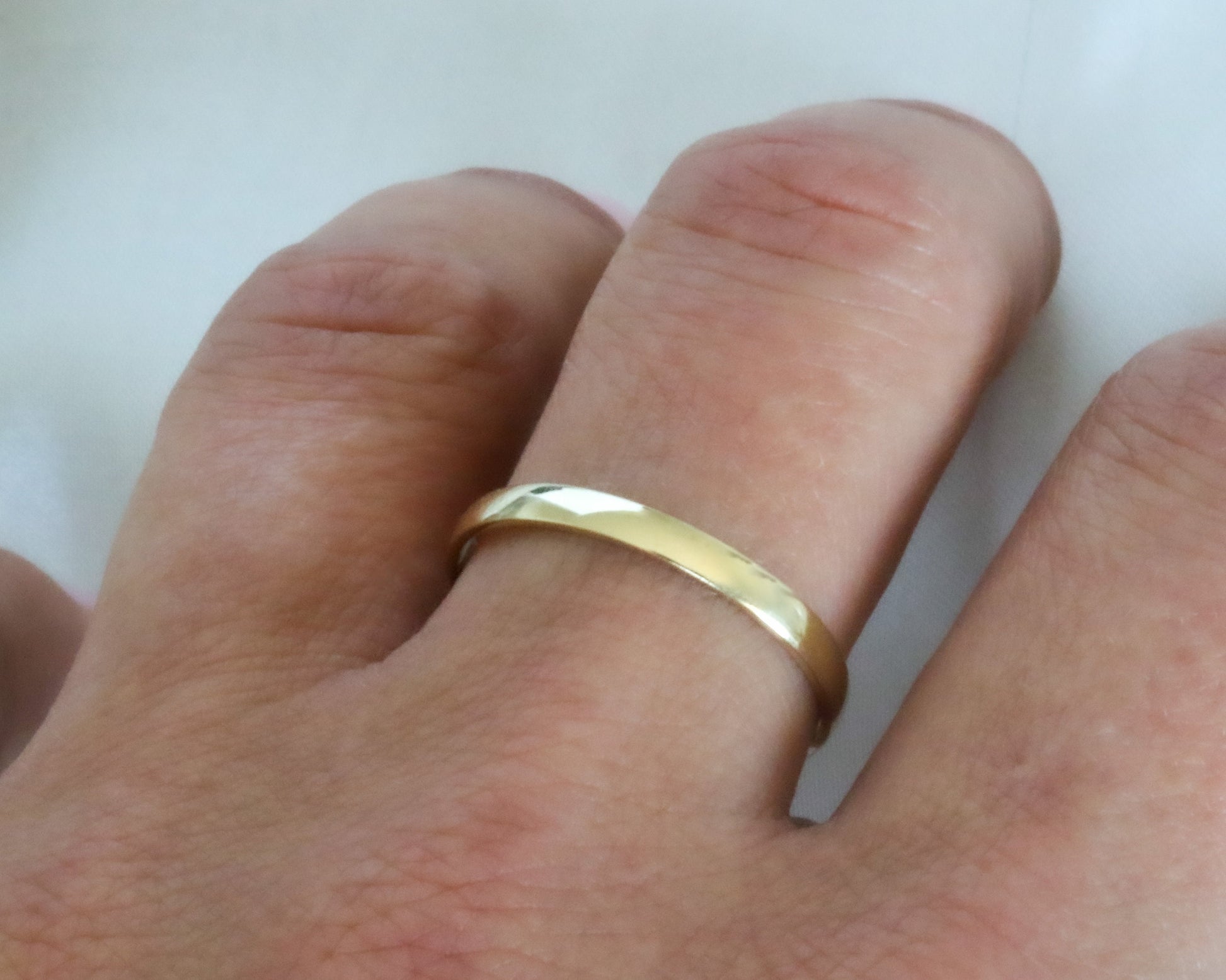 Gold ring on a person's finger against a white background