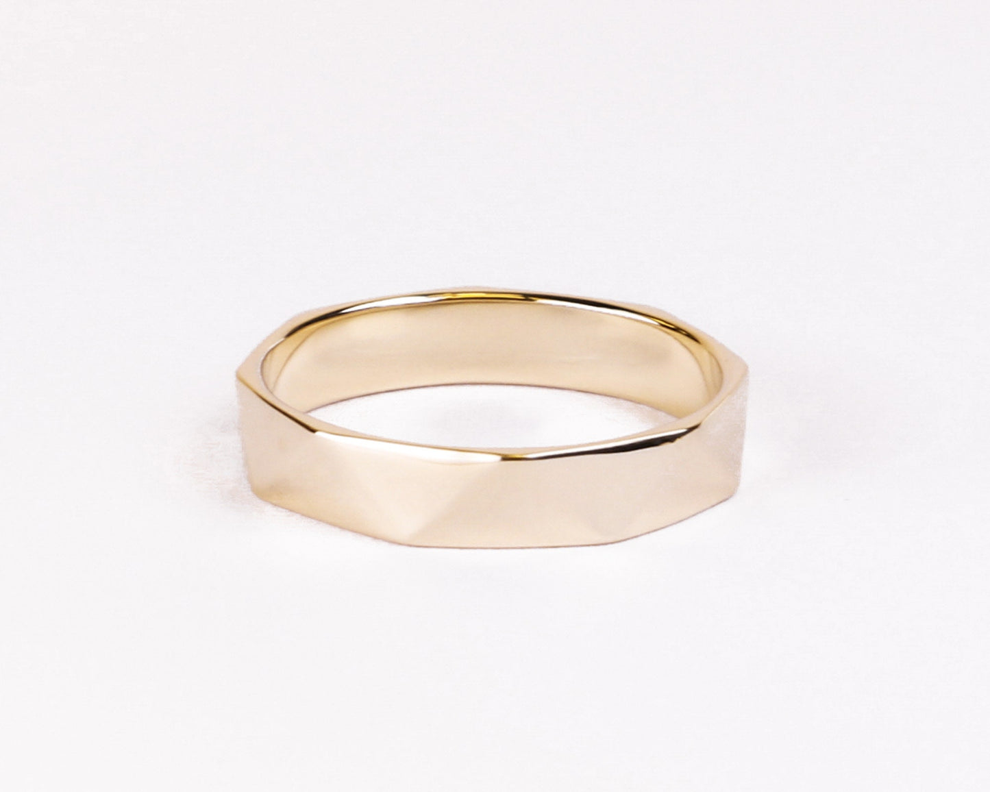 gold faceted wedding band flat lay white background