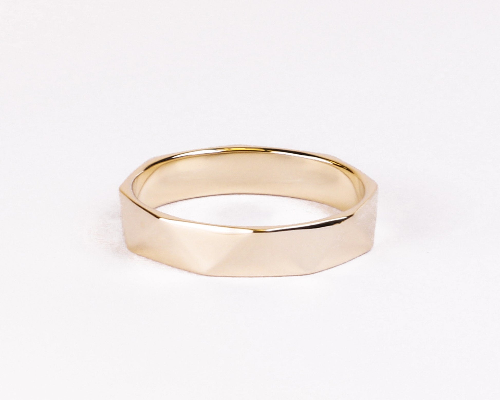 gold faceted wedding band flat lay white background