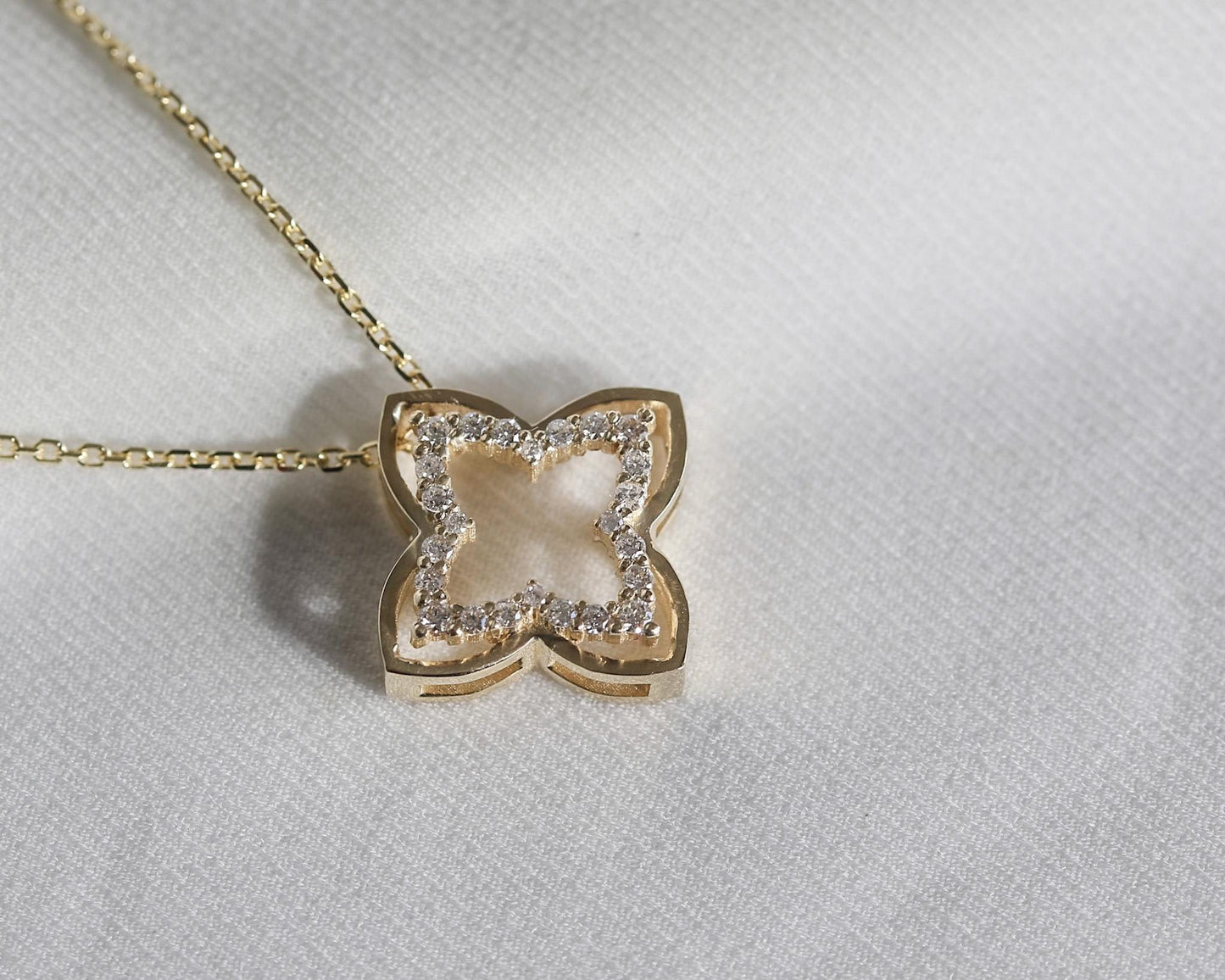 Butterfly-shaped pendant with diamonds on a gold chain against a light gray background