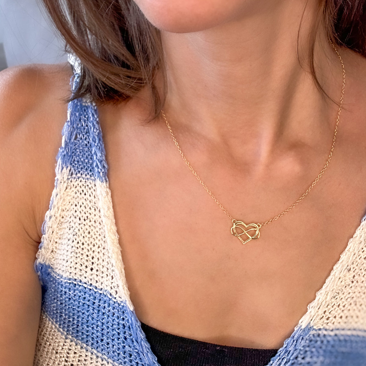 Yellow gold heart infinity necklace worn at the neckline