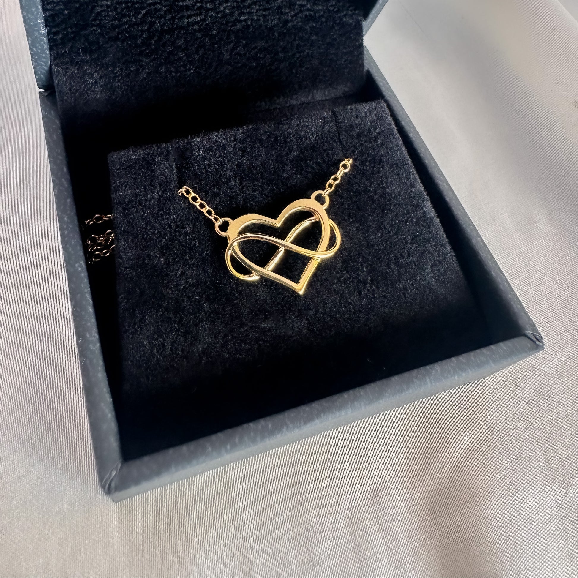 yellow gold heart and infinity symbol pendant and chain in black velvet box