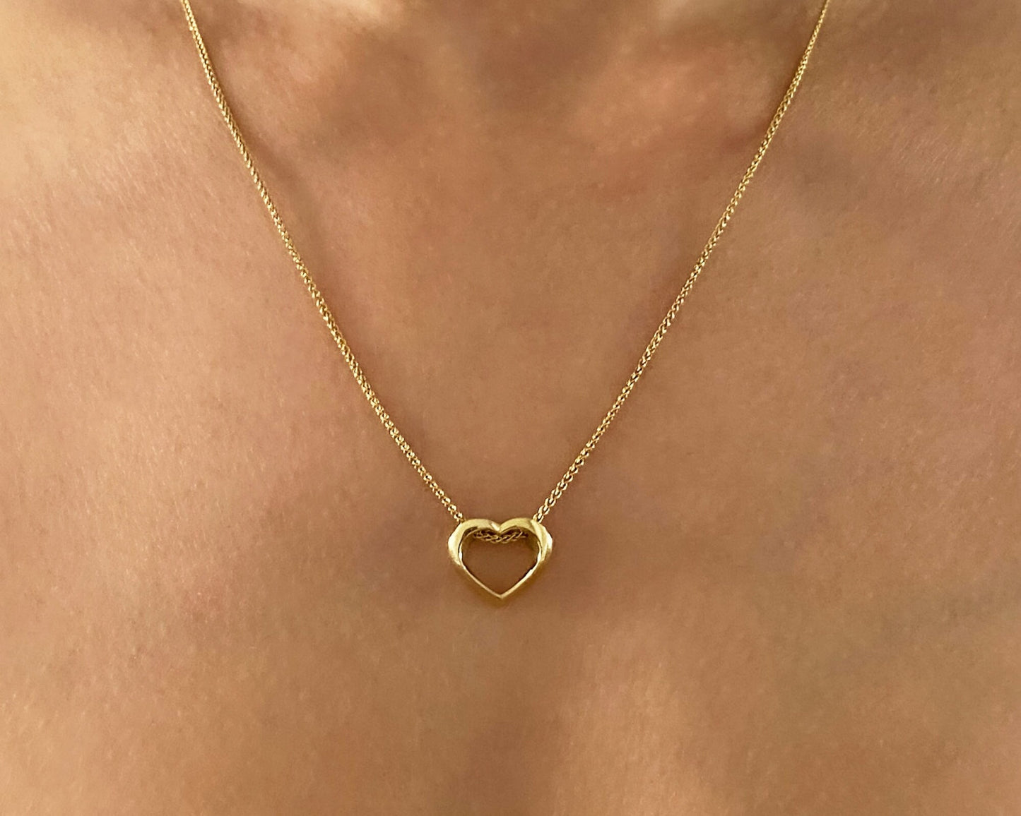 Gold heart-shaped necklace on a person's neck