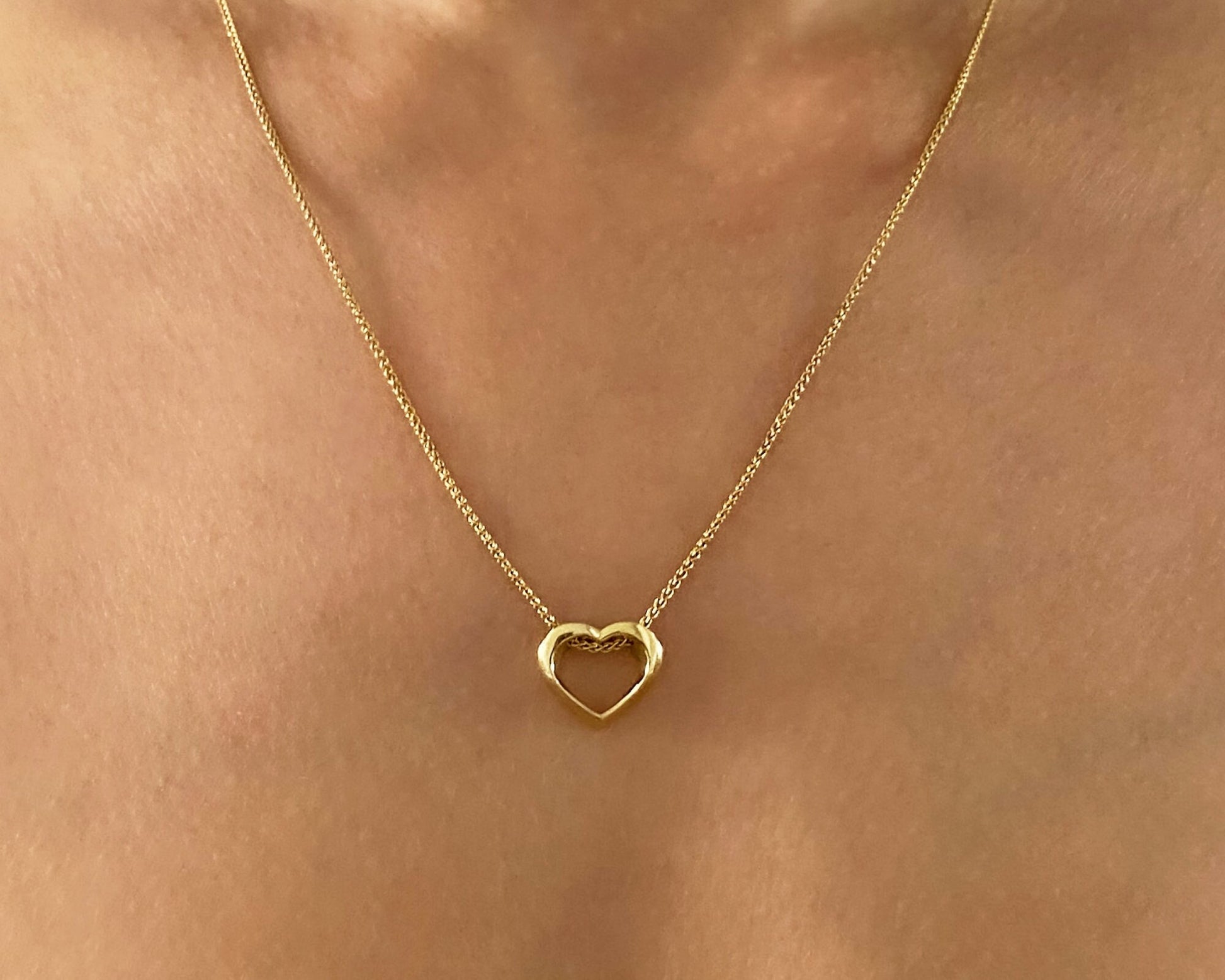 Gold heart-shaped necklace on a person's neck