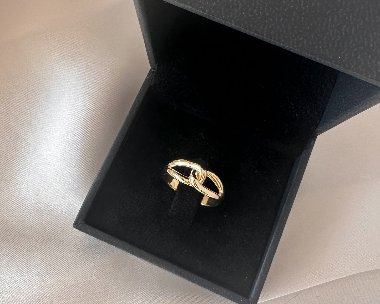Gold infinity knot ring presented in a black gift box