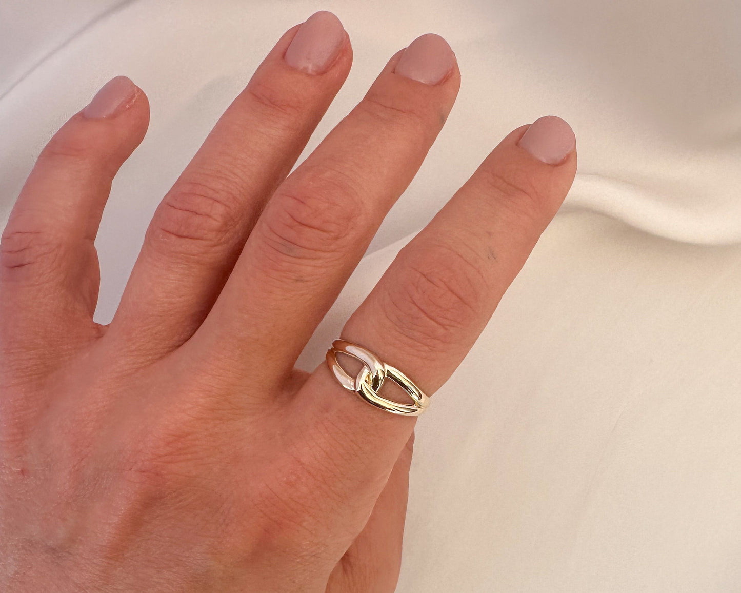 Gold love knot ring worn on the hand, angled view