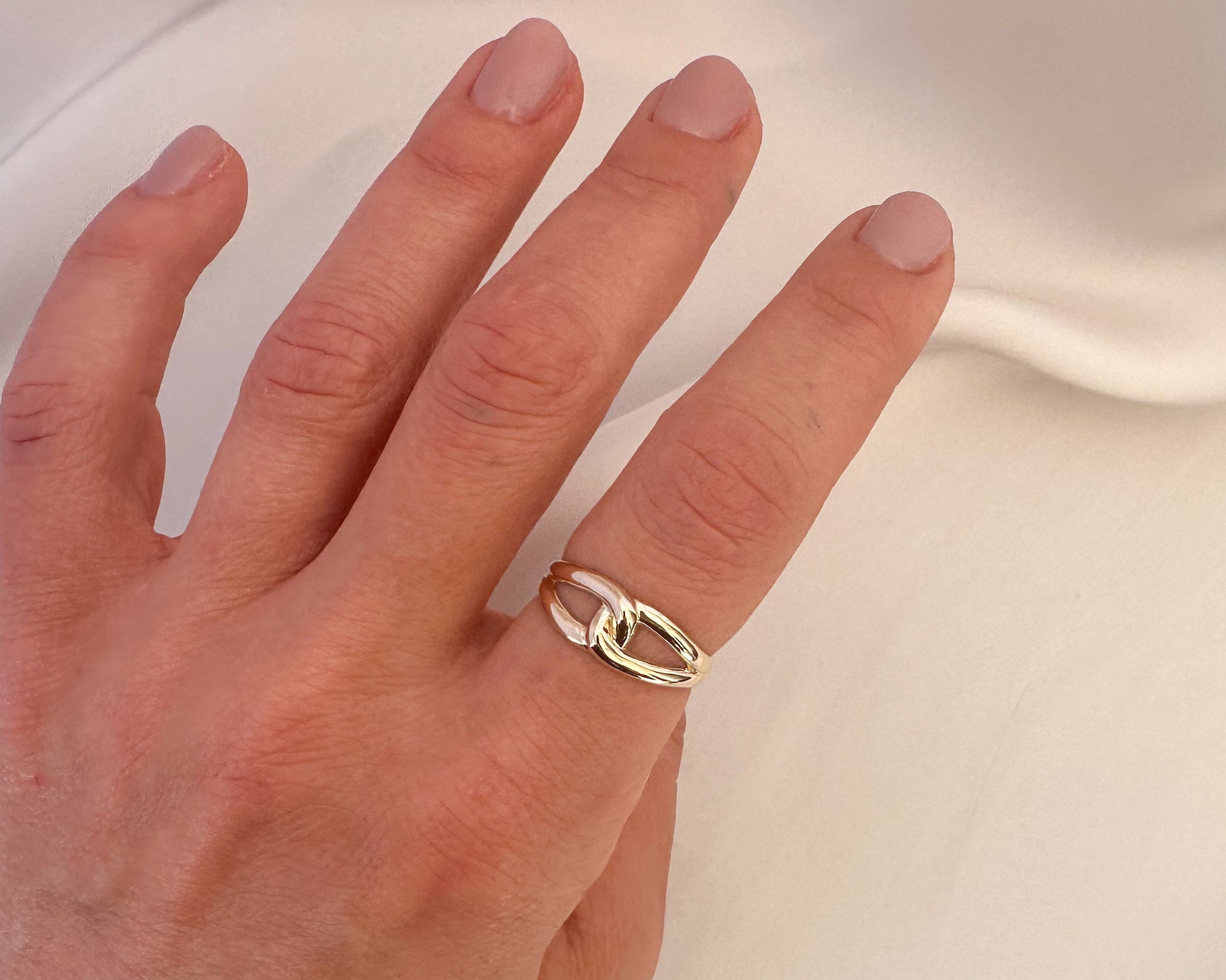 Gold love knot ring worn on the hand, angled view