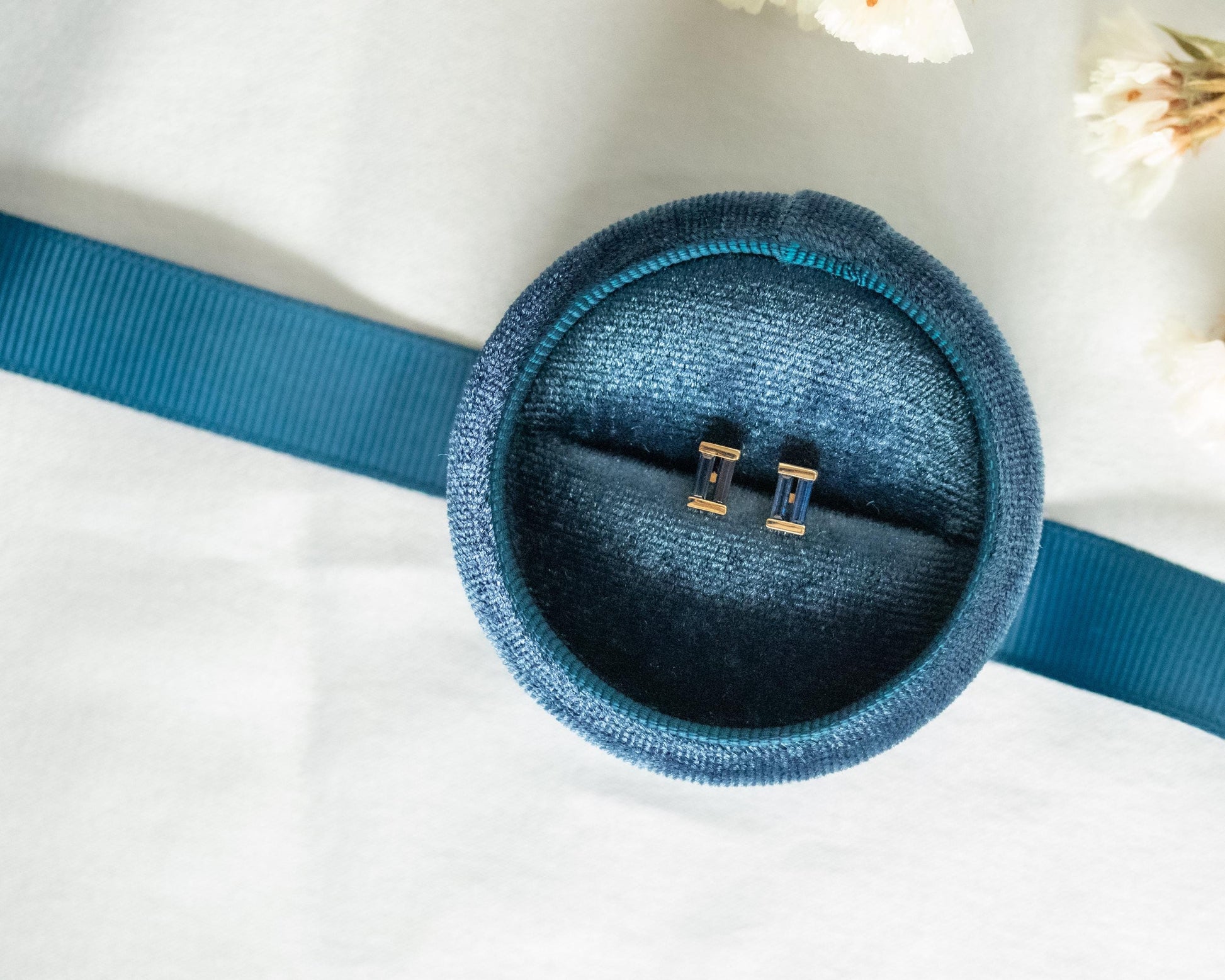 Gold baguette blue sapphire stud earrings styled with dried flowers