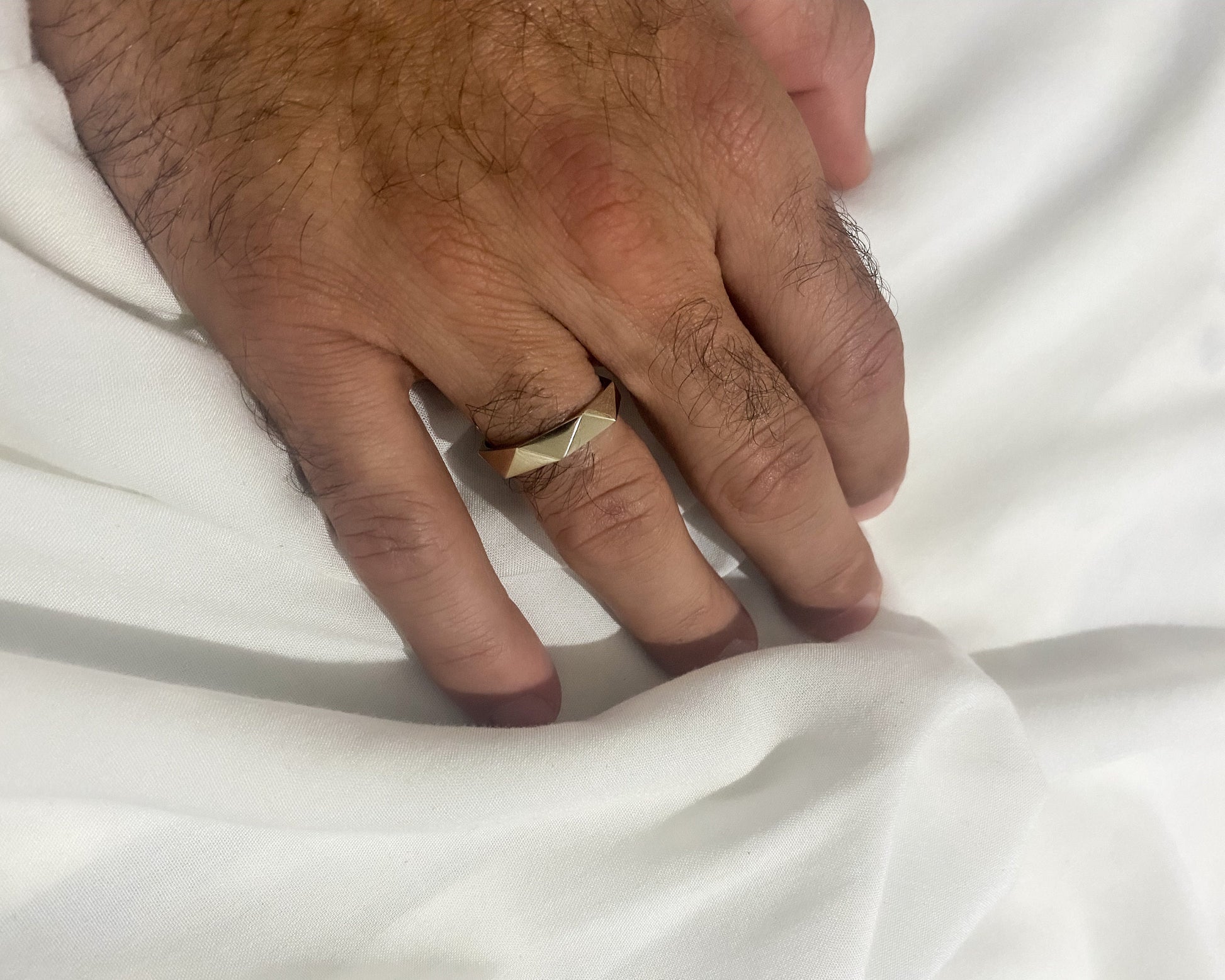 gold wedding band worn on hand white fabric backdrop