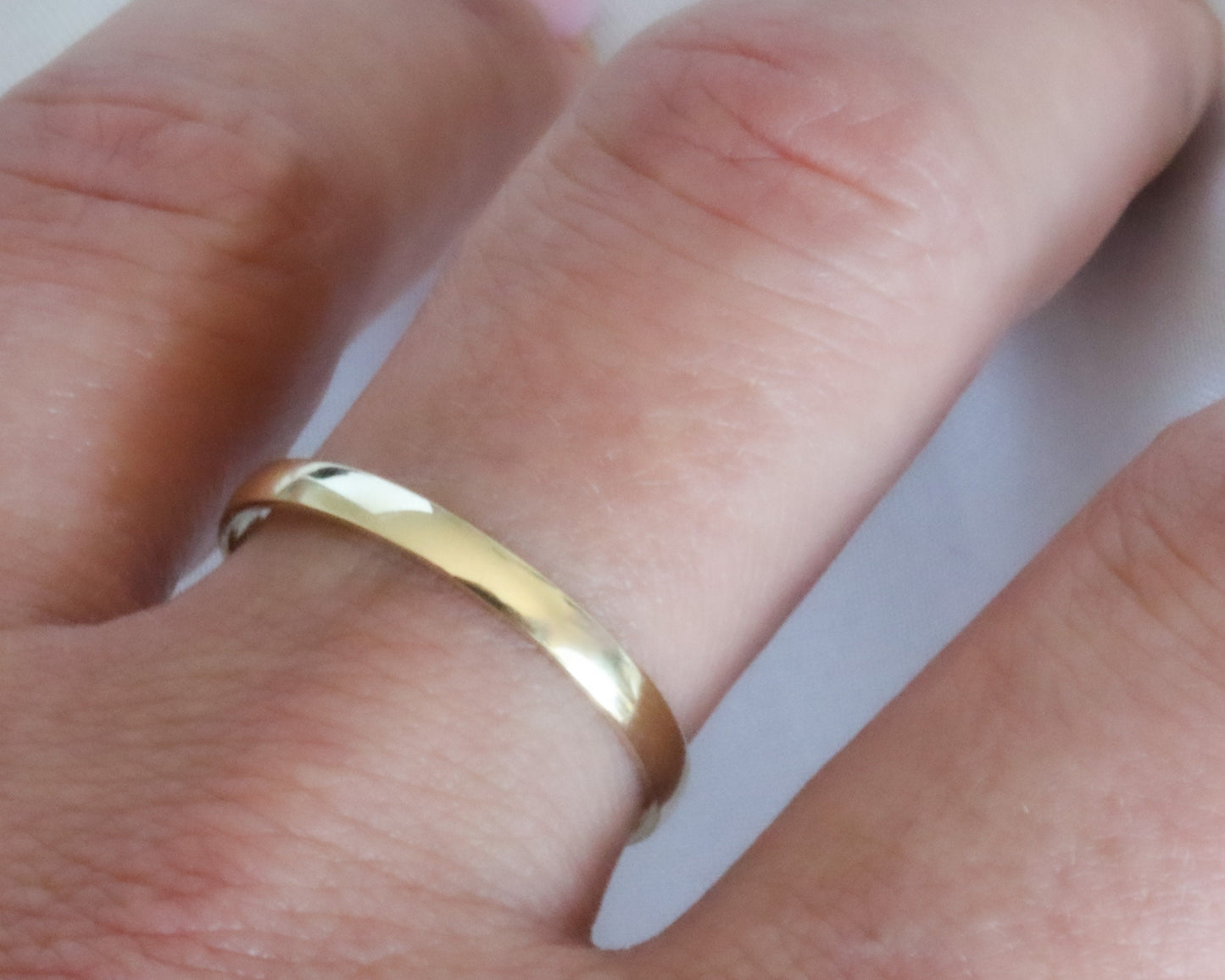 Gold ring on a finger with a plain background