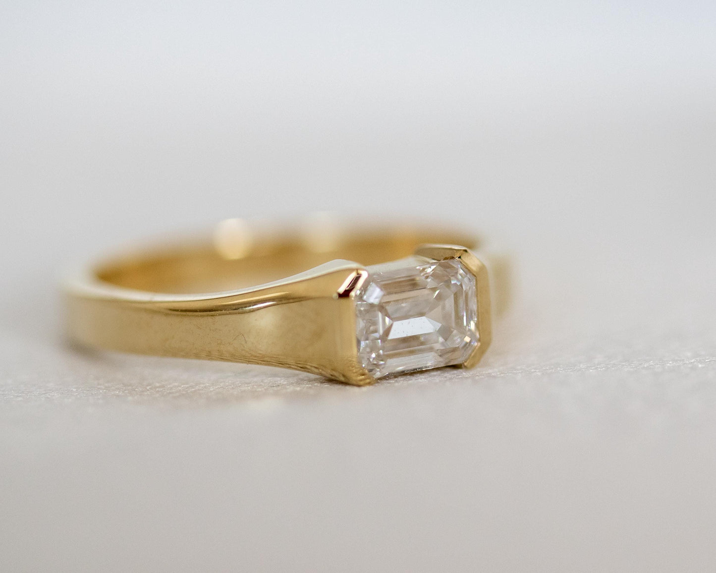 Gold ring with a rectangular diamond on a light background