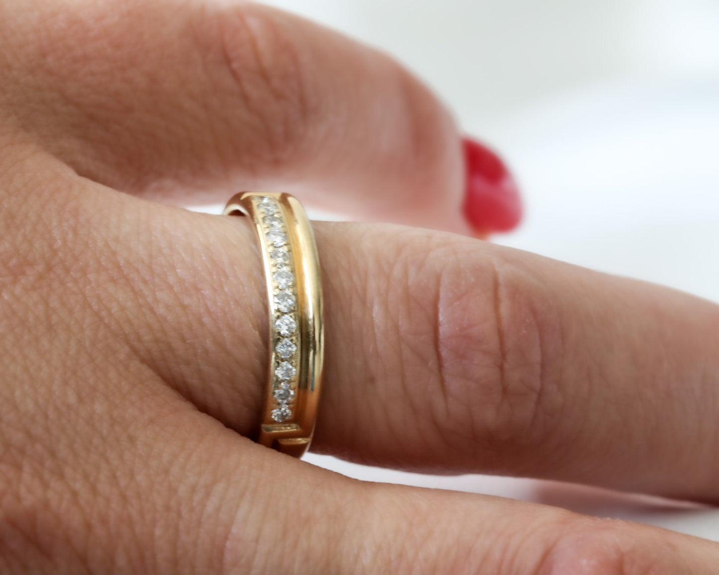 hand wearing diamond gold ring with red nails