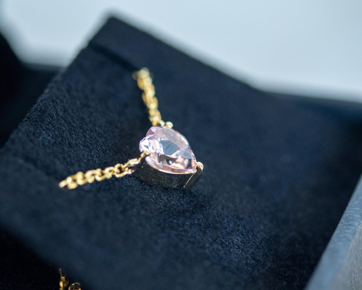 Heart shape morganite pendant on a 14K yellow gold rolo chain in a black jewelry box, angled view