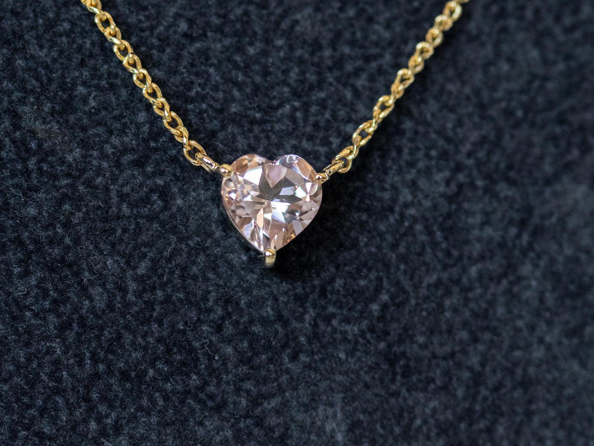 Heart shape morganite pendant on a 14K yellow gold rolo chain on dark blue fabric