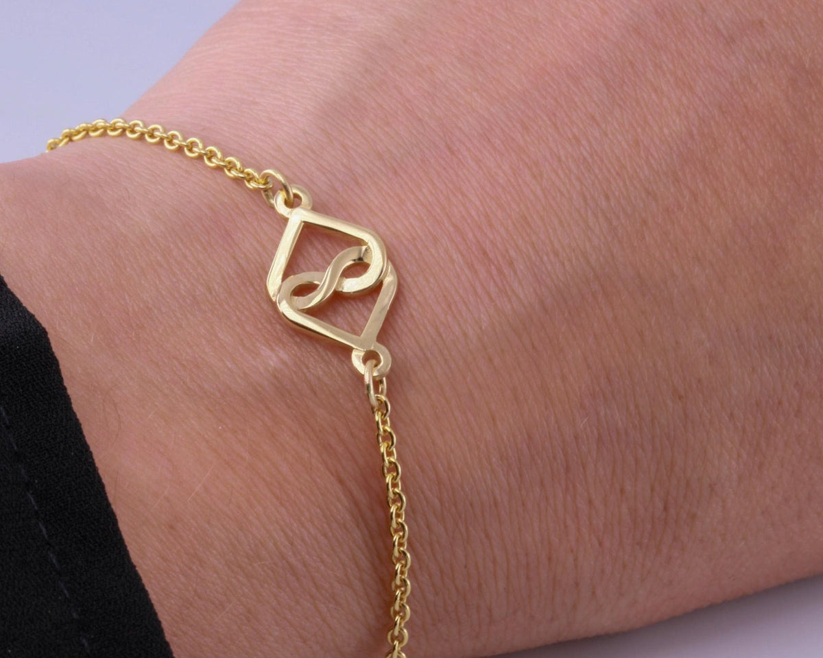 14K yellow gold rolo chain bracelet with an infinity heart charm, worn on the wrist