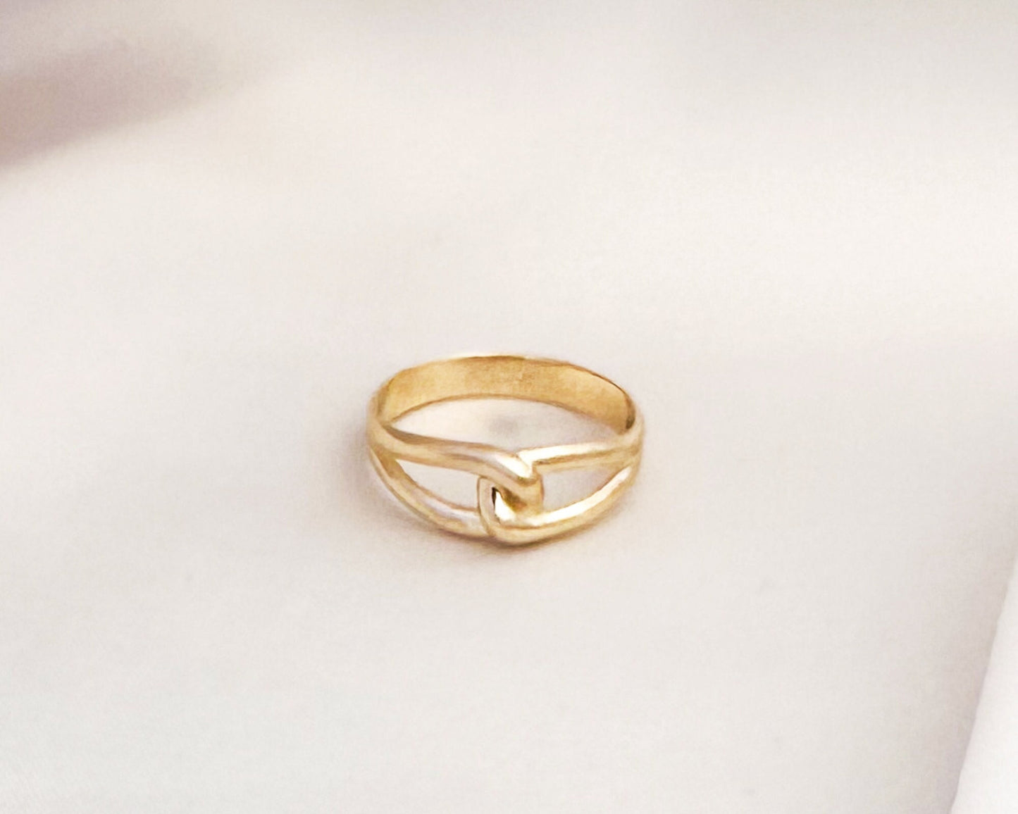 Solid gold infinity love knot ring on white fabric