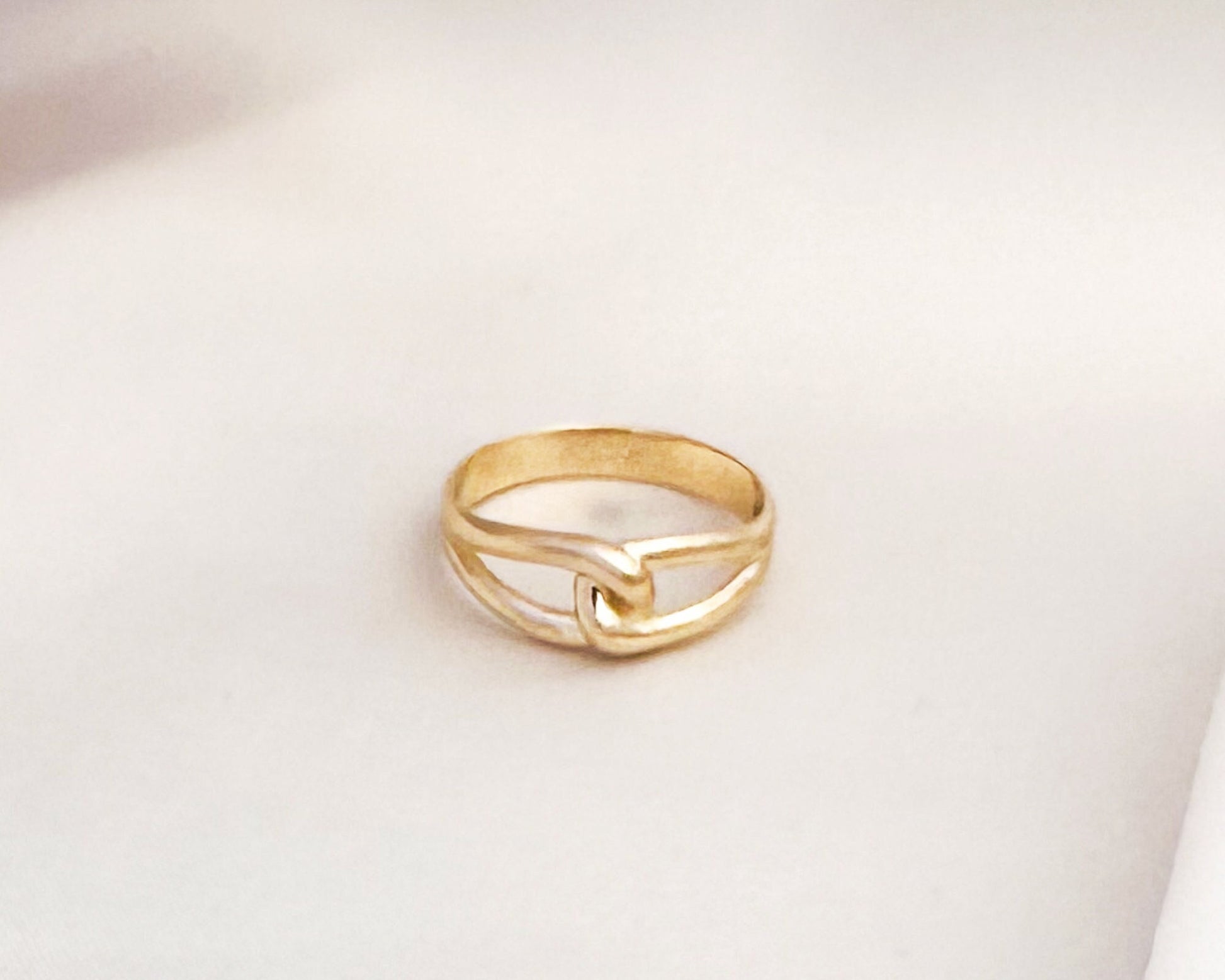 Solid gold infinity love knot ring on white fabric