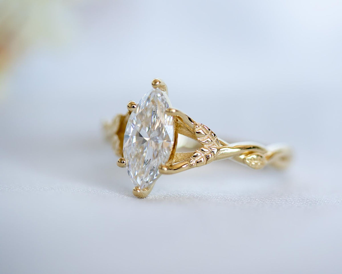 Close-up of a marquise diamond in a prong setting between two gold vines