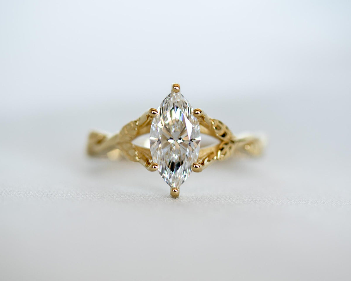 Marquise diamond engagement ring in yellow gold, set north-south between two twisted vines with leaves