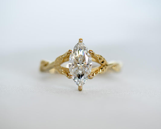 Marquise diamond engagement ring in yellow gold, set north-south between two twisted vines with leaves