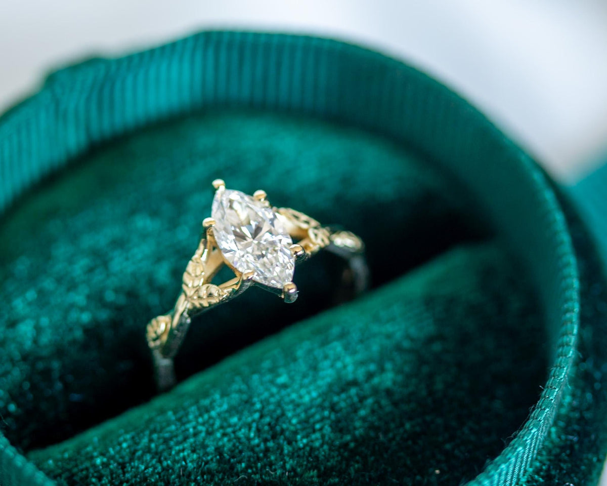 Marquise diamond engagement ring with a vine and leaf band in a teal velvet ring box