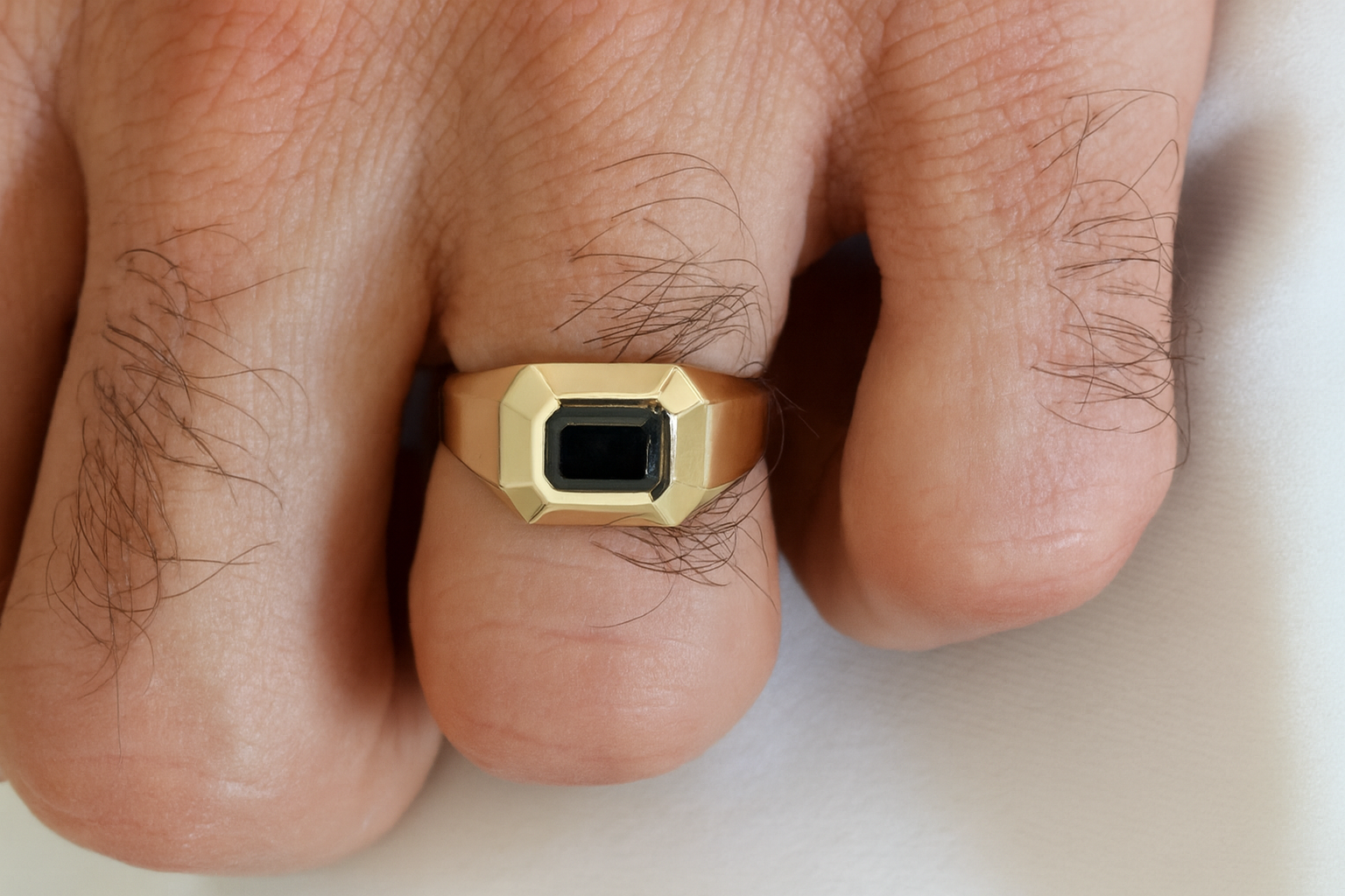 Men’s 14K yellow gold signet ring with emerald-cut black diamond worn on a finger — bold geometric design
