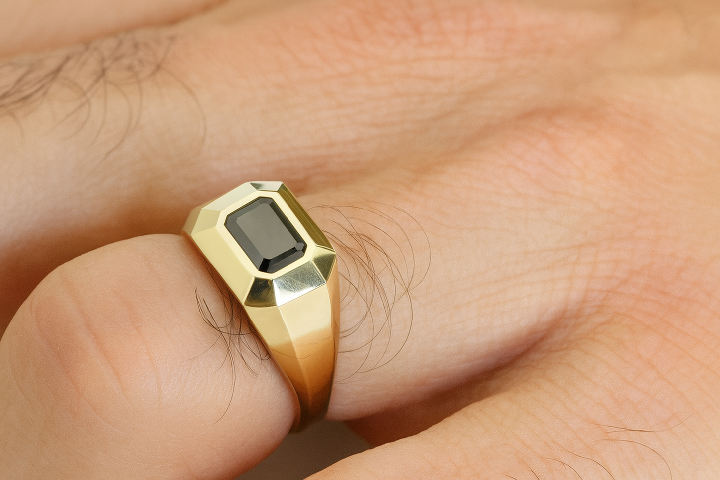 Men’s 14K yellow gold signet ring with emerald-cut black diamond, worn on a male hand