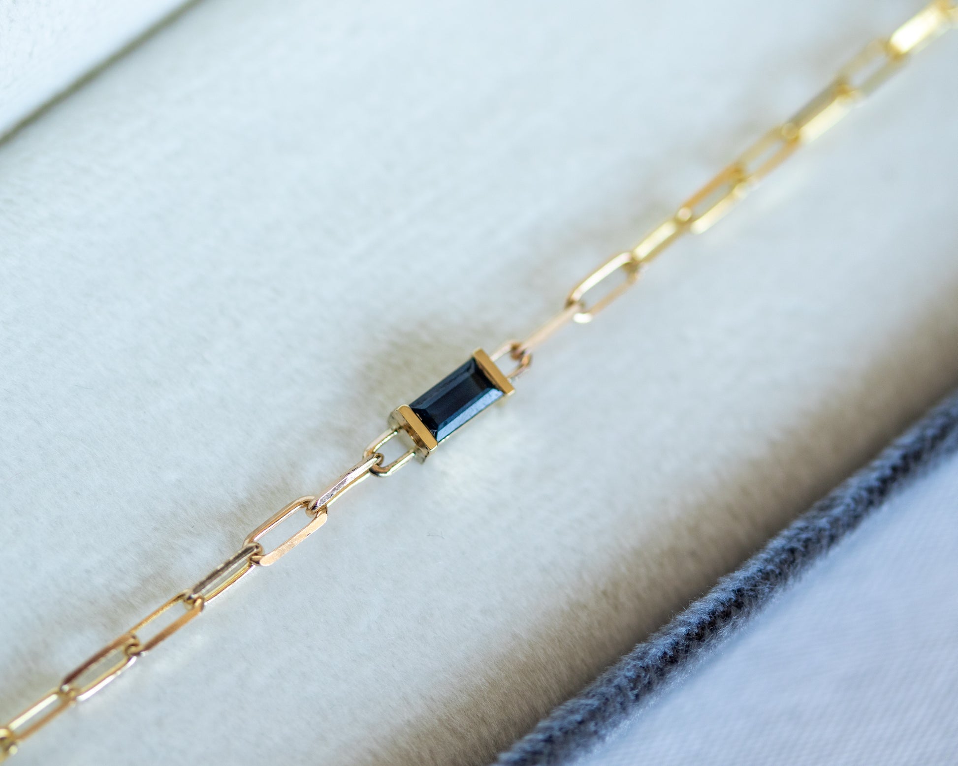 Gold bracelet with a blue baguette cut sapphire on white background
