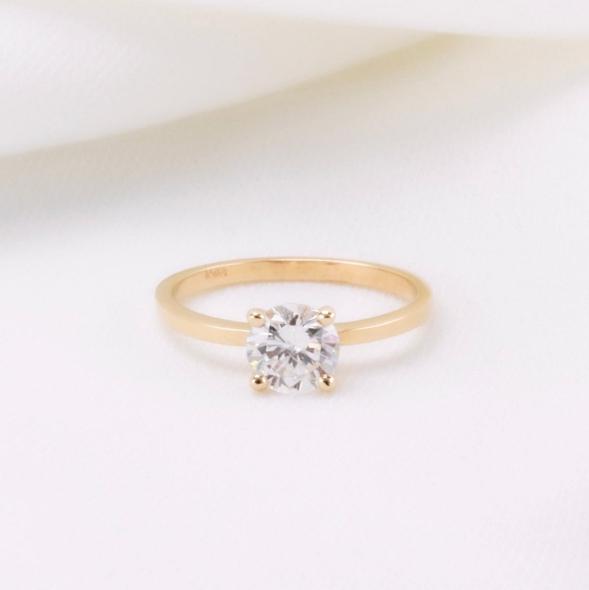 Minimalist four-prong round diamond solitaire ring in yellow gold, front view