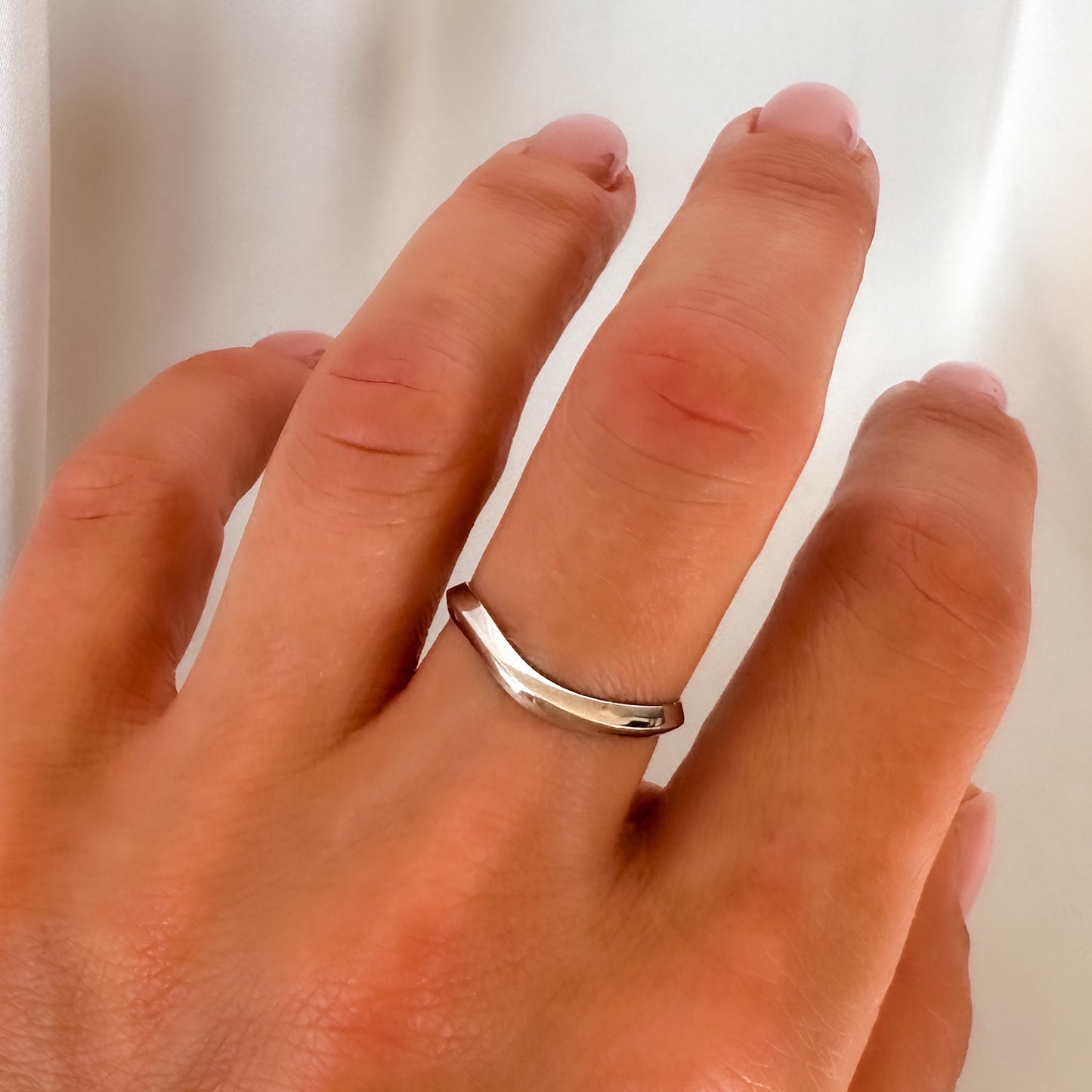 A 14K gold ring with a modern geometric wavy design, sitting on a womens finger